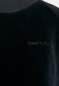 Top in velluto nero con una texture liscia, caratterizzato da un logo ricamato "BIMBA Y LOLA" in un colore abbinato sul davanti.