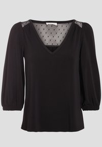 Blouse noire avec un col en V, des panneaux d'épaule en mesh transparent à pois et des manches bouffantes. Tissu lisse, coupe décontractée et poignets élastiques.