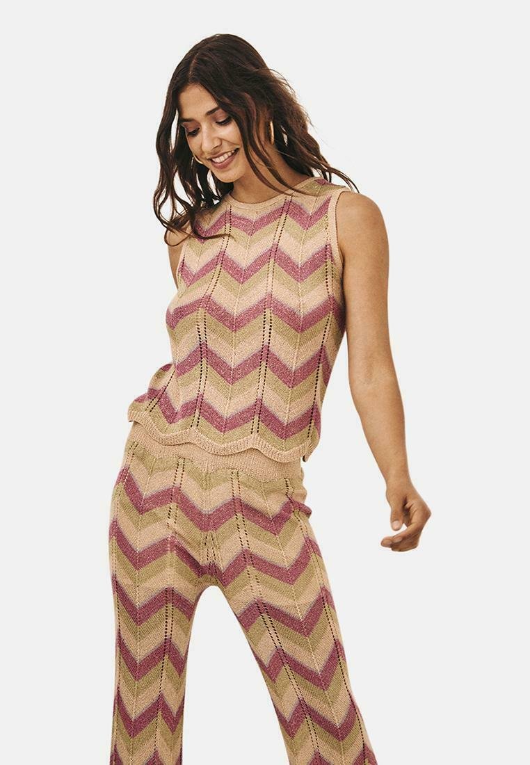 Top sin mangas y pantalones de color beige con un patrón de zigzag en rosa y verde. El dobladillo festoneado y los detalles de calado añaden textura.