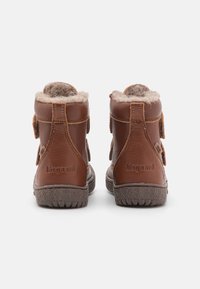 Pár hnědých dětských kožených bot s chlupatou podšívkou, viditelným šitím a texturovanou gumovou podrážkou, pohled zezadu.