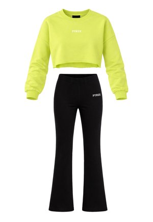 Felpa corta giallo neon con maniche lunghe e pantaloni neri a zampa d'elefante, entrambi con i loghi bianchi "PYREX" sul petto e in vita.