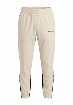 Beige Sergio Tacchini trainingsbroek met elastische tailleband, zwarte zijstrepen, ritssluitingen bij de enkels en een logo op de bovenste linker dij.