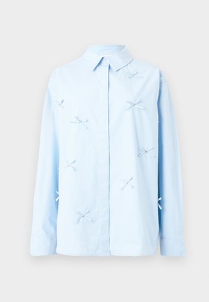 Light blue shirt made of cotton with a collar, featuring decorative embroidered bows and beads across the front. Long sleeves, button closure.