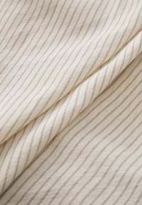 Lys beige stoff med smale vertikale striper i en mørkere nyanse. Myk tekstur med en lett glans, som gir et glatt, drapert utseende.