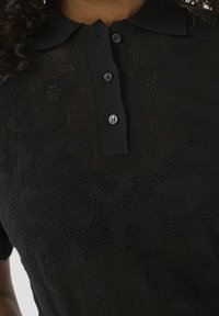 Černé pletené polo tričko s květinovým vzorem, krátké rukávy a čtyři knoflíky na léze.