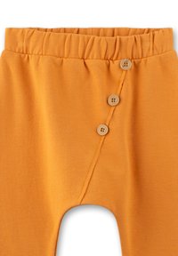 Orange Baumwollhosen mit einem lockeren Bund, ausgestattet mit drei Holzknöpfen und einem diagonalen Nahtdetail. Weicher Stoff, taillierte Passform.