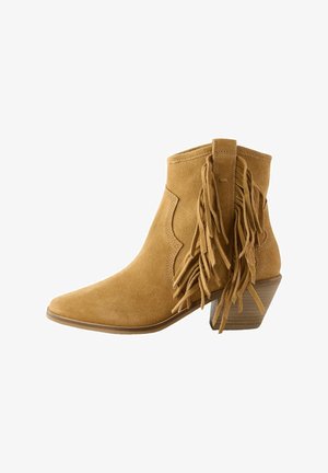 Botte de cheville en daim jaune moutarde avec un bout pointu, présentant des franges au niveau du talon et un talon en bois empilé.
