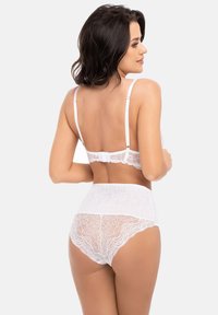 Set di lingerie in pizzo bianco con un delicato motivo floreale. Il reggiseno ha spalline regolabili e chiusura a gancio; le mutandine a vita alta presentano dettagli in pizzo coordinati.