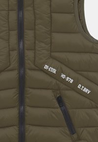 Olivgrön vadderad väst med quiltad design, blixtlås framtill och två blixtlåsförsedda fickor. Har vita textaccenter på tyget.