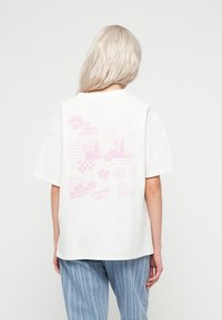 Tricou alb din bumbac cu croială lejeră, având pe spate desene grafice roz pal. Include texte și motive florale.