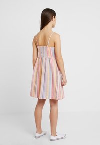 Abito estivo a righe con spalline sottili regolabili, schiena arricciata e gonna svasata in colori pastello tra cui rosa, giallo e blu.