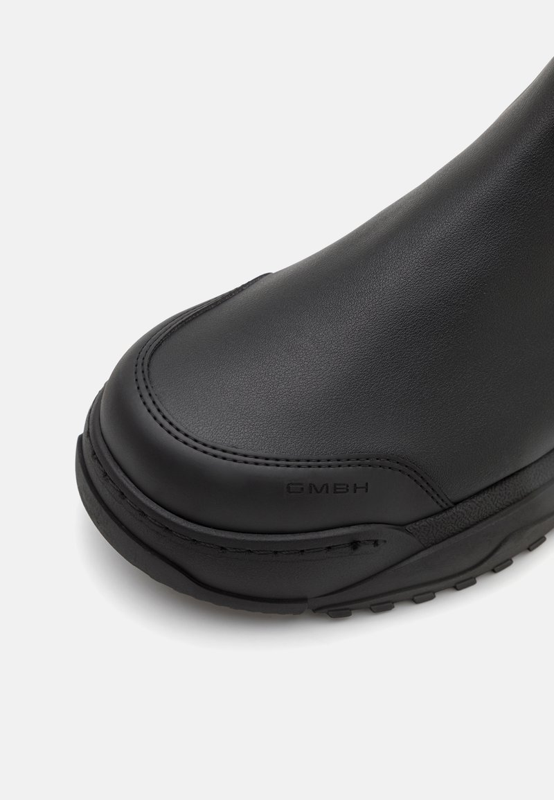 Zwarte leren enkellaars met een ronde neus, gladde textuur en gegraveerd merk aan de zijkant. Gestructureerd ontwerp met rubberen zool.