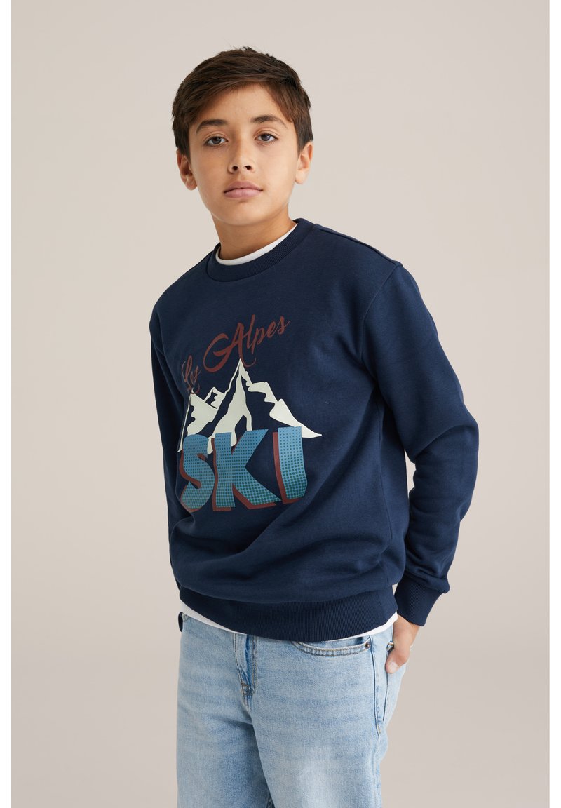 Tmavě modrá mikina s grafikou hor, nápisy "Les Alpes" a "SKI" v červené a modrozelené barvě. Kulatý výstřih, žebrované manžety a pas. Volný střih.