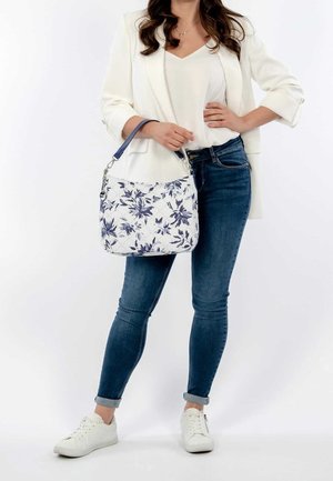 Borsa a tracolla con motivo floreale nei colori bianco e navy. Materiale in tela morbida, di dimensioni medie, con tracolla navy staccabile e dettagli in metallo argentato.