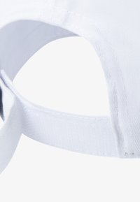 Cappello bianco con forma arrotondata, realizzato in cotone. Presenta un design ricamato e una cinghia regolabile sul retro.