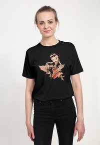 Camiseta de algodón negra con un personaje ilustrado montando una criatura alada, con una pancarta de cinta roja, que muestra un estilo y colores vintage.