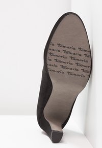 Semelle d'une chaussure à talon haut noire avec le nom de la marque Tamaris embossé à plusieurs reprises sur le dessous, taille 38.