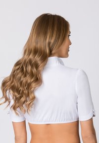 Weiße, kurze Bluse mit kurzen Ärmeln, die ein tailliertes Design und einen gerafften Saum aufweist. Glattes Material mit leichtem Glanz. Keine sichtbaren Muster.