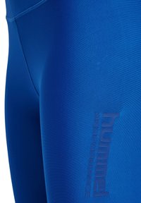 Blå träningsleggings i mjukt, stretchigt material. Har en diskret präglad logotyp på sidan och en figurnära passform.