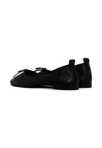 Bailarinas de cuero negro con detalle de lazo, tacón bajo, parte trasera texturizada y punta suave; presentan un diseño clásico para uso informal.