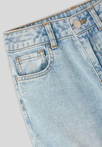 Jeans in denim blu chiaro con una finitura sbiadita, caratterizzati da cuciture arancioni, un bottone metallico di chiusura e un piccolo dettaglio sulla tasca anteriore.
