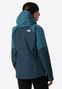 Teal and dark navy blue waterproof jacket with a hood, featuring a logo on the back, long sleeves, and a smooth texture.