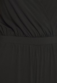 Tissu noir avec une texture froncée et une couture de ceinture définie, montrant des coutures détaillées et des plis doux.