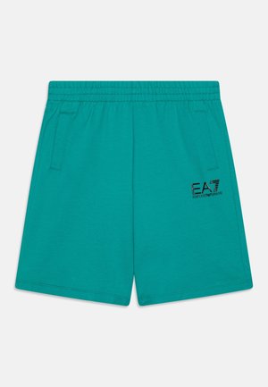 Shorts en coton turquoise avec une taille élastique, des poches latérales et un logo brodé noir sur la jambe gauche. Texture lisse, design décontracté.