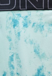 Κοντινό πλάνο υφάσματος ανοιχτού μπλε με πιο σκούρα μπλε αφηρημένα μοτίβα και μερική μαύρη ζώνη μέσης με ανοιχτό γκρι ραφές.