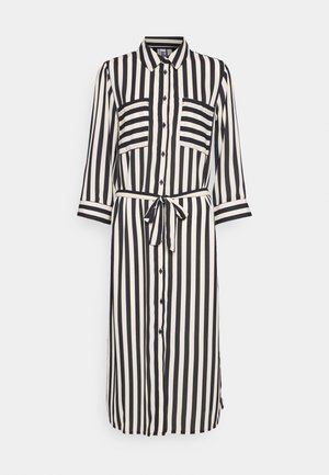 Robe chemise midi à rayures verticales noires et blanches manches longues, boutons sur le devant, deux poches poitrine et ceinture à nouer à la taille.