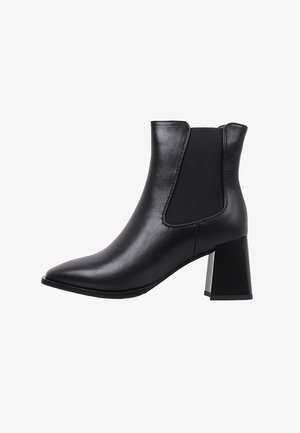 Botín de cuero negro hasta el tobillo con puntera puntiaguda, tacón cuadrado y paneles laterales elásticos. Textura suave con un detalle mínimo.