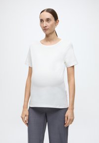 Λευκό μαιευτικό μπλουζάκι με κοντά μανίκια και στρογγυλή λαιμόκοψη, με χαλαρή εφαρμογή που προσαρμόζεται στην αναπτυσσόμενη κοιλιά, με απαλή υφή από βαμβάκι.