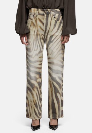 Straight-leg jeans med beige og brun zebra print, båret med sorte spidse hæle og en mørk bluse med lange ærmer.