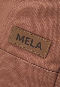 Roestkleurige stoffen tas met een gestructureerd oppervlak. Bevat een rechthoekig leren label met "MELA" in donkere letters geperst.