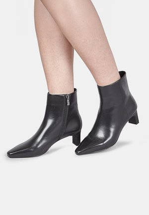 Black leather ankle boots with a pointed toe, side zipper, and a square heel. Smooth texture and minimalist design.