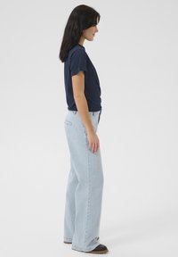 Navy blue cotton t-shirt paired with light blue wide-leg jeans. Jeans feature a relaxed fit, and both items have a plain design without patterns.