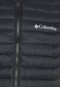 Giacca a vento nera con design a cucitura orizzontale, dotata di una cerniera centrale e di un logo bianco Columbia sul lato sinistro. Texture liscia.