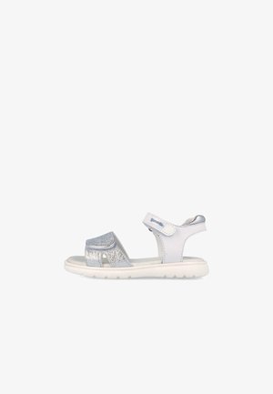 Sandalía blanca y plateada para niño, con correas ajustables de velcro y suela acolchada, mostrada de lado sobre un fondo blanco.