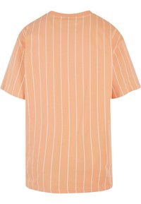 T-shirt à manches courtes en pêche avec des rayures verticales blanches, fabriqué en tissu doux. Présente un col rond et une coupe décontractée, style boxy.