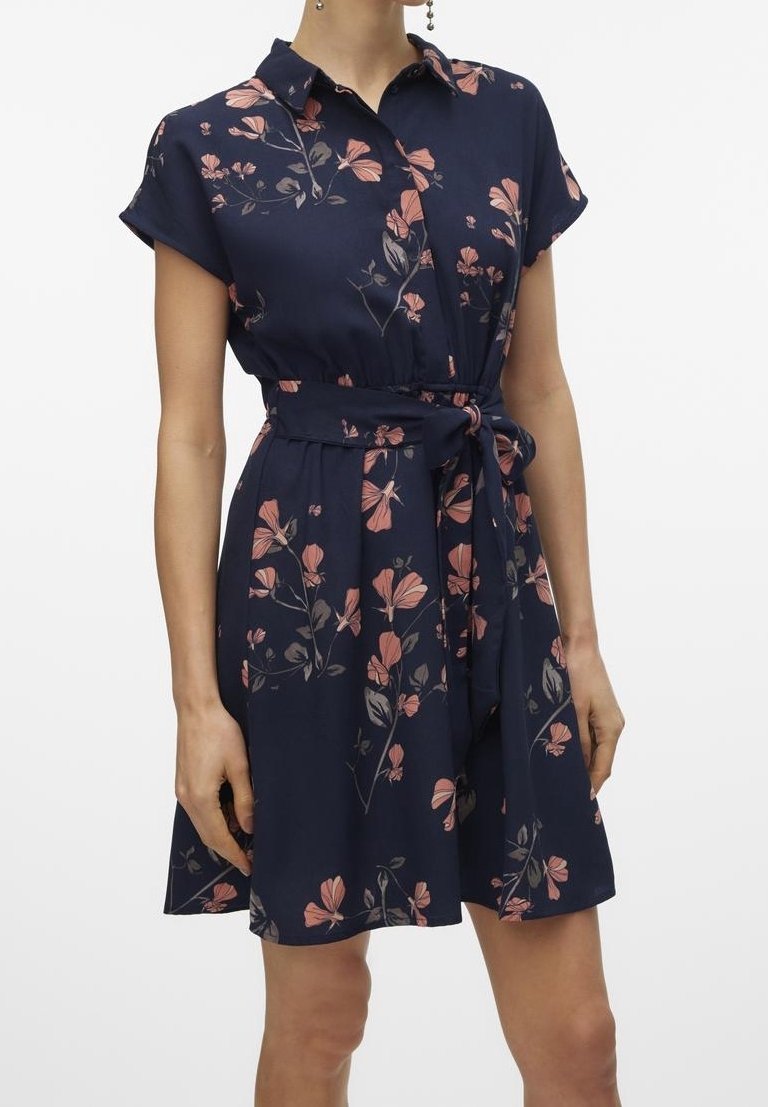 Robe bleu marine à manches courtes avec motif floral rose, col boutonné, devant avec boutons et ceinture à la taille portée par une femme.