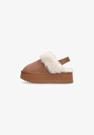 Bruine suède platform slipper met een witte nepbont kraag en achterkantriem. Beschikt over een gestructureerde, gelaagde zool voor grip en comfort.