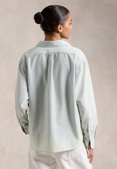 Világos menta zöld színű, lazán illeszkedő, hosszú ujjú ing, ívelt aljjal, puha, texturált anyagból készült.