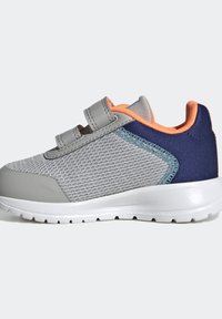 Šedé síťované tenisky s námořnickými a oranžovými akcenty, s gumovou podrážkou a nastavitelným popruhem, navržené pro pohodlí a oporu.