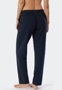 Marina blå pyjamasbyxor med vita prickar, med elastisk midja och lös passform, tillverkade av mjukt och lätt tyg.