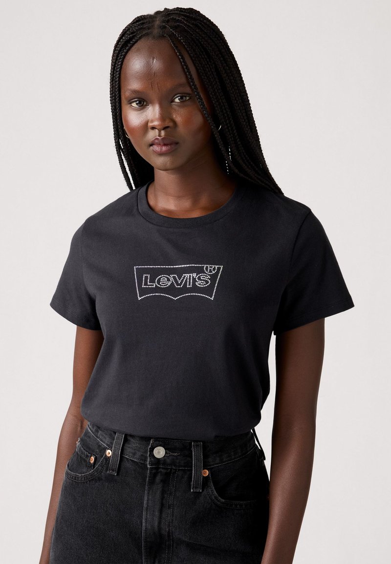 T-shirt in cotone nero con logo bianco di Levi's. Collo a giro, maniche corte, abbinato a jeans neri a vita alta.