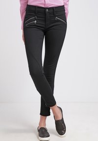 Černé denimové kalhoty se zipovými kapsami, slim fit a hladkou texturou. Mají klasický pětikapsový design a středně vysoký pas.