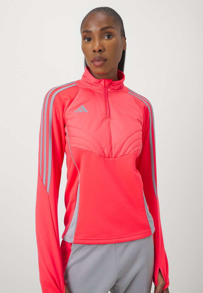 Helle pinkfarbene Sportjacke mit hohem Kragen, grauen Akzenten und einem Viertelreißverschluss. Verfügt über strukturierte Einsätze und lange Ärmel.