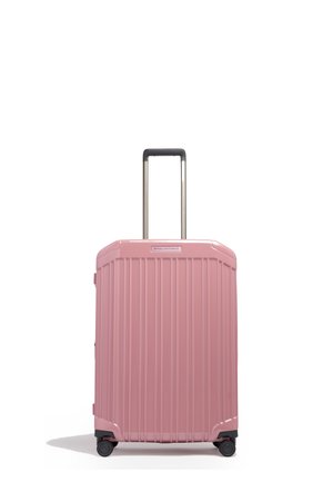 Hardcase roze koffer met verticale ribben, vier wielen en een uitgeschoven zwart handvat op een witte achtergrond.