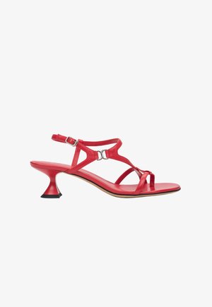 Crvena kožna sandala s više remenčića, otvorenim prednjim dijelom i prepoznatljivom visokim potpeticom proširenog oblika s crnim naglaskom. Podesiva kopča oko gležnja.
