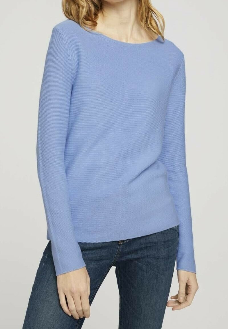 Pull en tricot côtelé bleu clair avec un col bateau et des manches longues, associé à un jean foncé, avec une texture lisse.